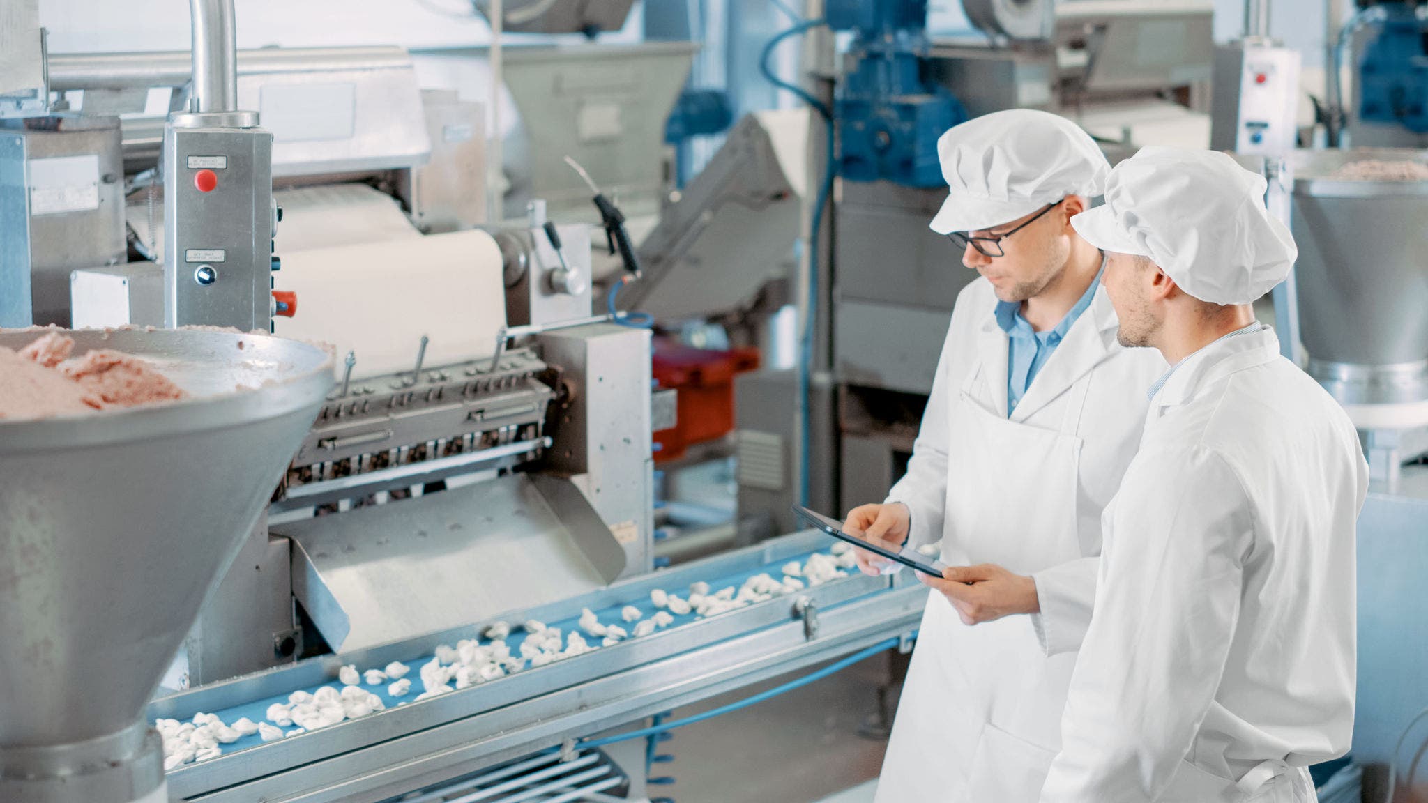 Two Young Male Quality Supervisors or Food Technicians are Inspecting the Automated Production at a Dumpling Food Factory. Employee Uses a Tablet Computer for Work. They Wear White Work Robes.; Shutterstock ID 1791646958; purchase_order: Jasmin Zehnder