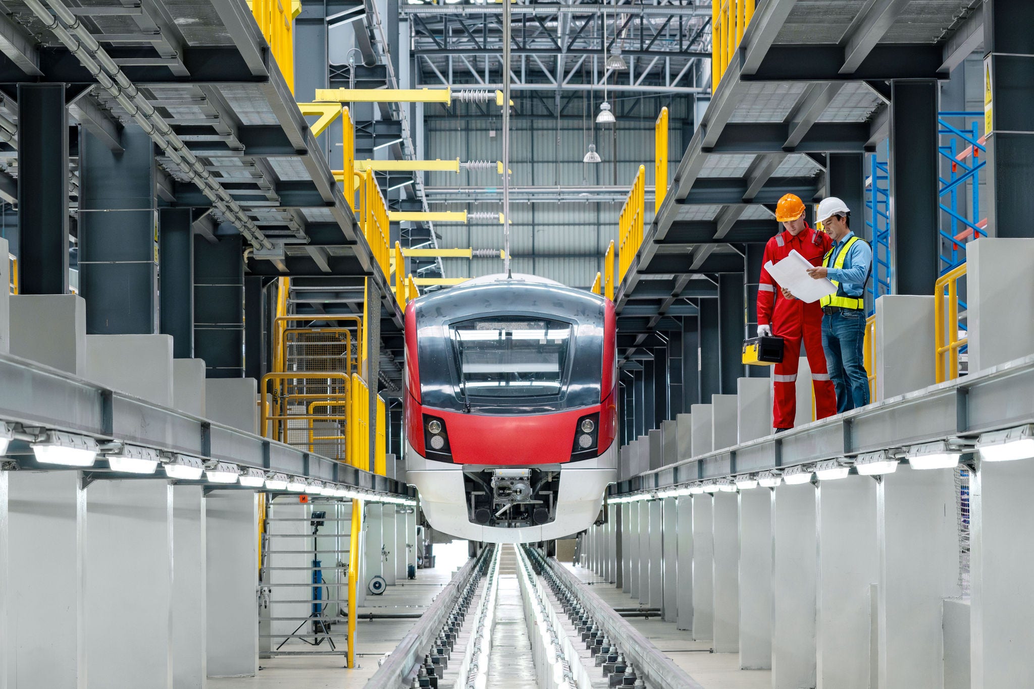 Electric train technician engineer with blueprints  checking controls system for security functions in maintenance infrastructure plant of sky train, public transportation vehicle,Teamwork management; Shutterstock ID 2381483415; purchase_order: Jasmin Zehnder