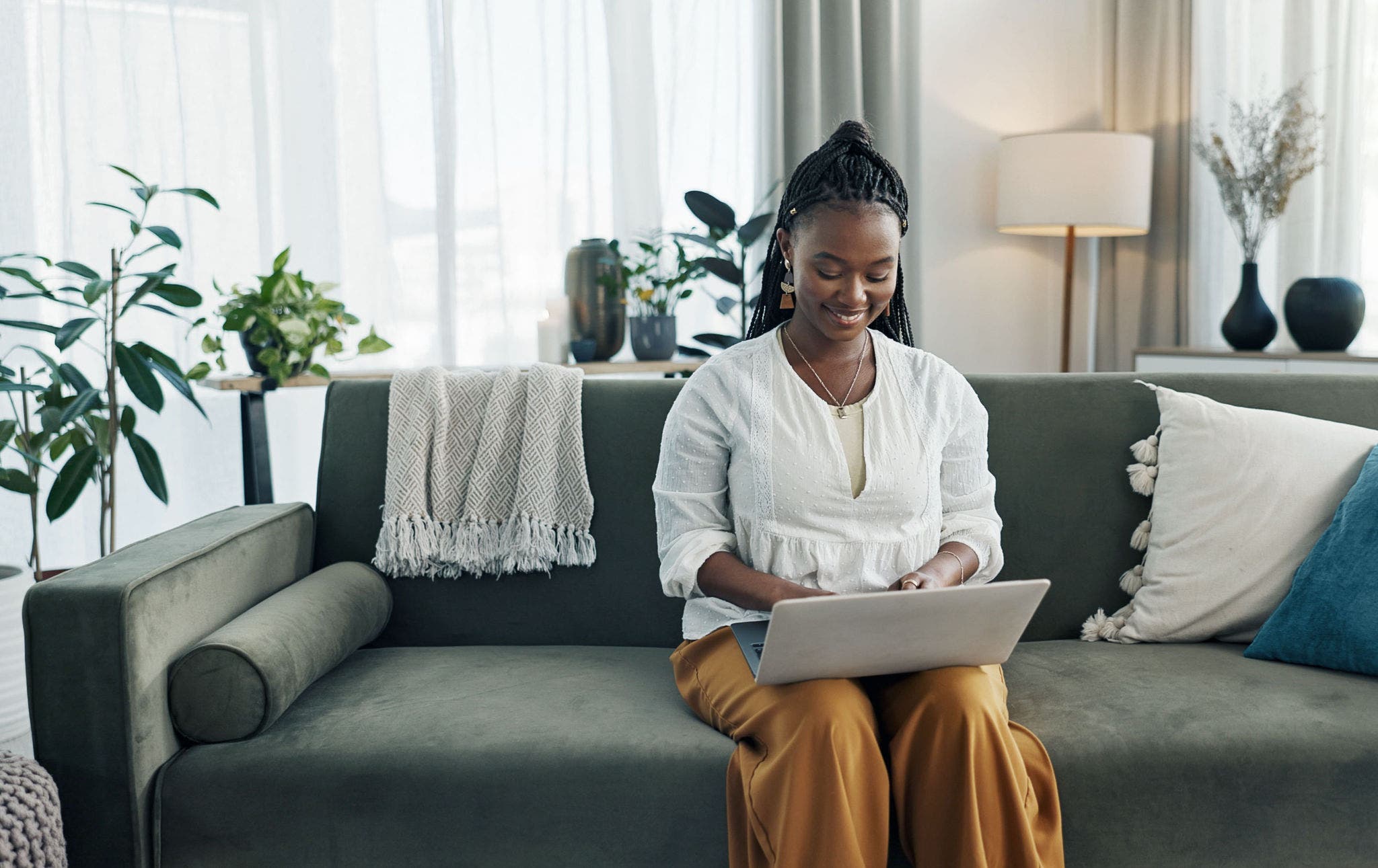 Black woman on sofa, smile and typing on laptop for remote work, social media or blog post research in home. Happy girl on sofa with computer checking email, website or online chat in living room.; Shutterstock ID 2422947193; purchase_order: Jasmin Zehnder