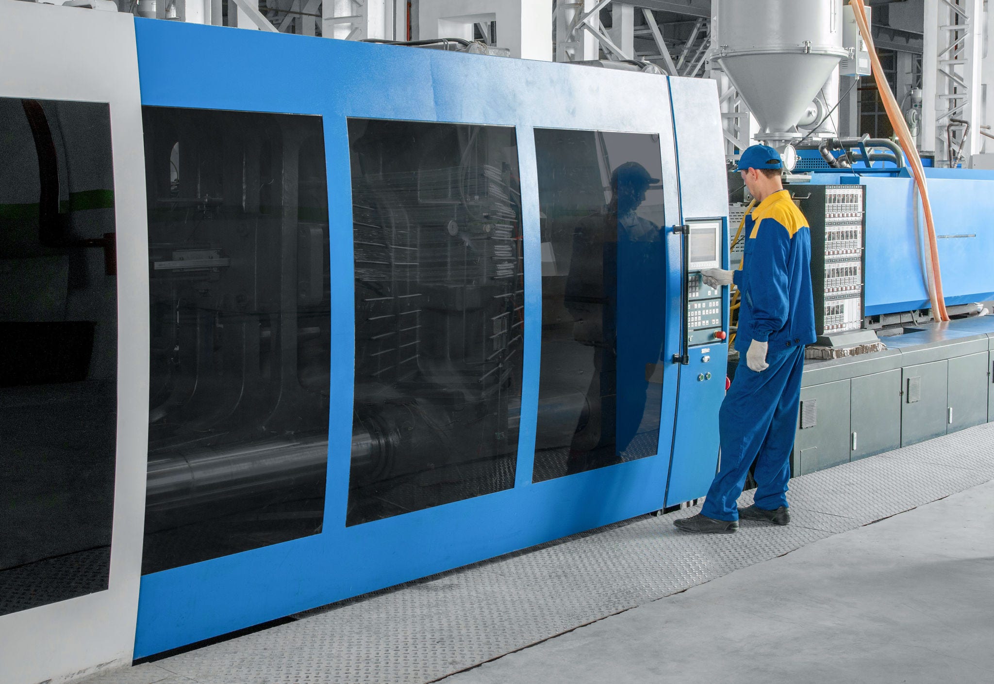 Industrial injection molding press machine for the manufacture of plastic parts using polymers in the management of worker; Shutterstock ID 537060817; purchase_order: Jasmin Zehnder