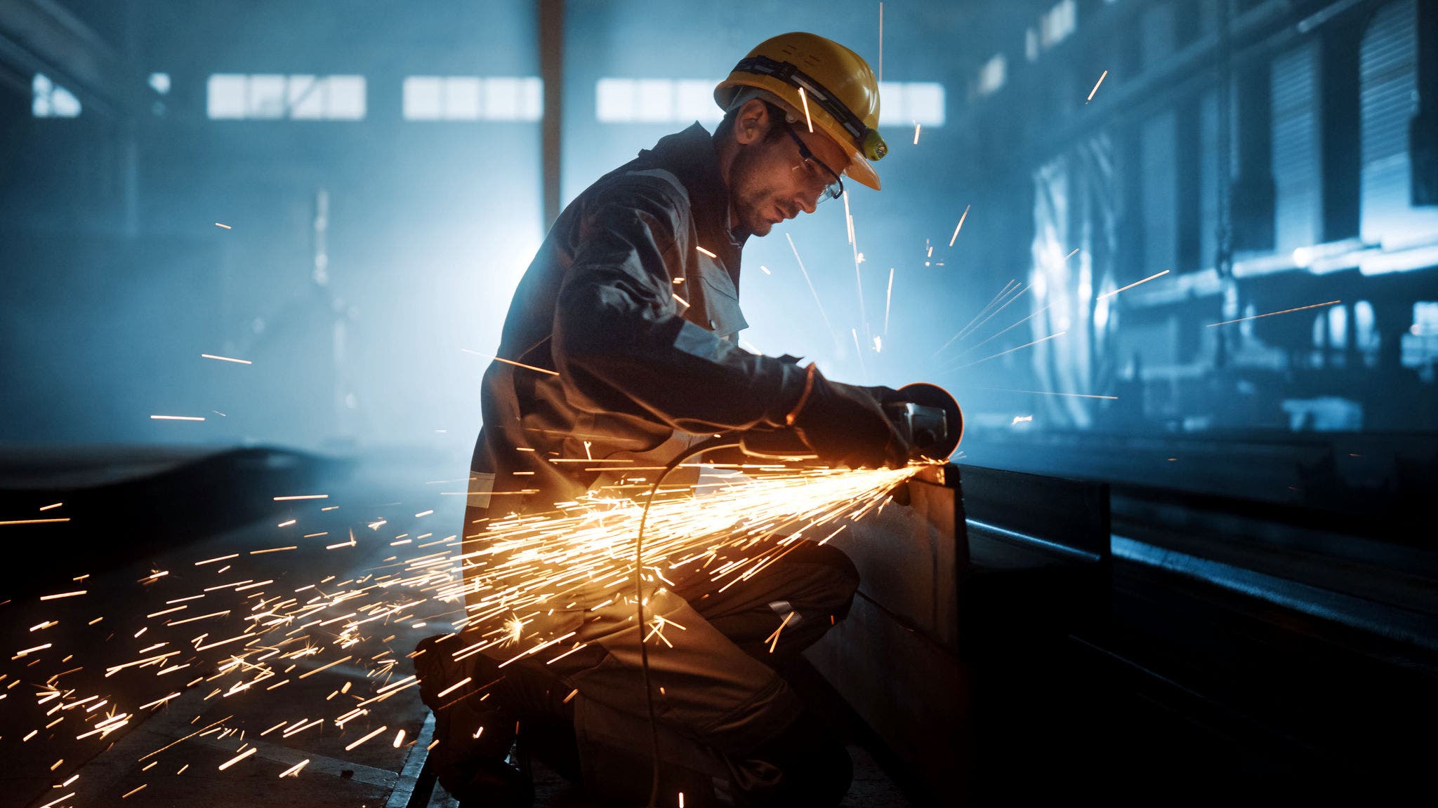 Heavy Industry Engineering Factory Interior with Industrial Worker Using Angle Grinder and Cutting a Metal Tube. Contractor in Safety Uniform and Hard Hat Manufacturing Metal Structures.; Shutterstock ID 1870491376; purchase_order: Jasmin Zehnder