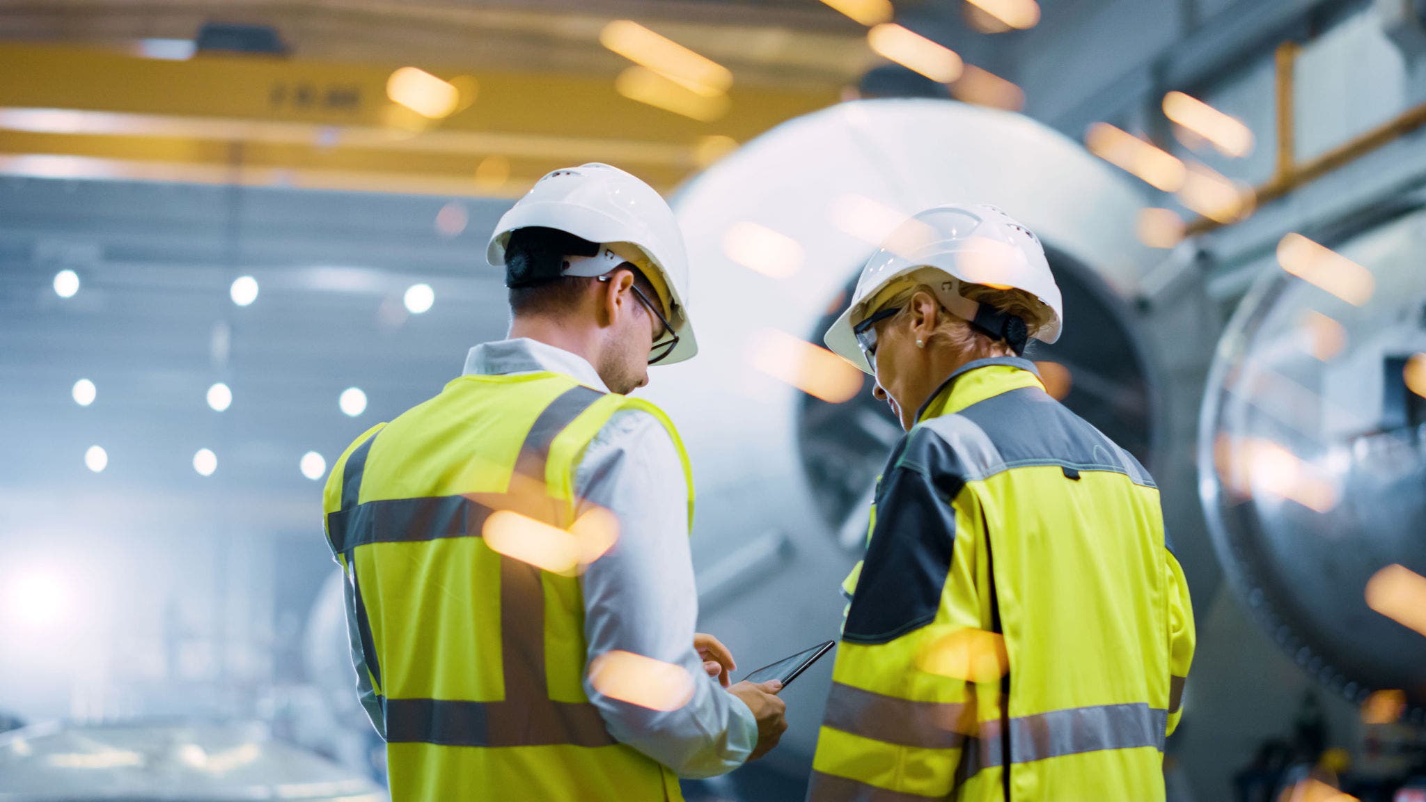 Two Heavy Industry Engineers Stand in Pipe Manufacturing Factory, Use Digital Tablet Computer, Have Discussion. Construction of Oil, Gas and Fuels Transport Pipeline. Back View Sparks Flying; Shutterstock ID 1727599432; purchase_order: Jasmin Zehnder