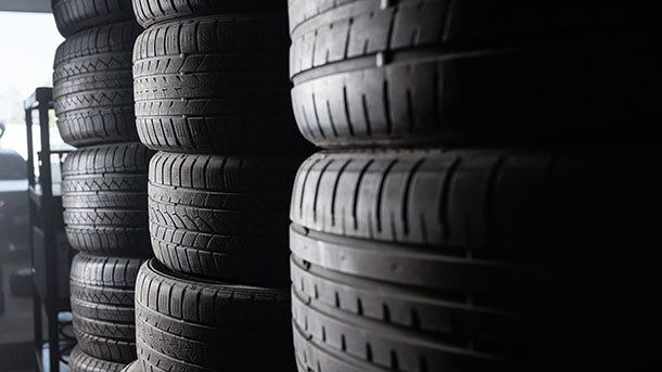 Sunlight in the tire storage. Stack of old tires in a car shop garage. Tire installation service.; Shutterstock ID 425834503; purchase_order: PLAS Pierre-Antoine