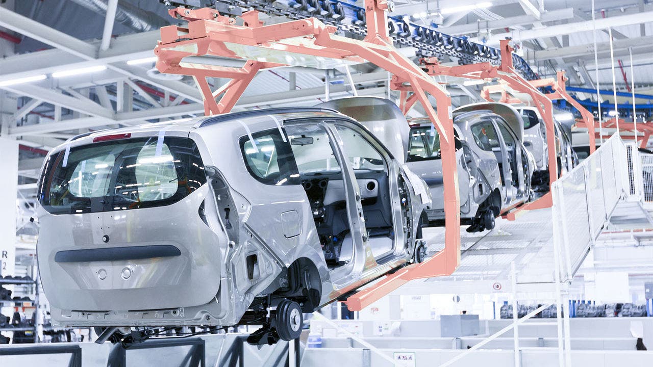 Car bodies suspended on an overhead conveyor system in an automotive factory, demonstrating efficient assembly line production and modern manufacturing infrastructure.