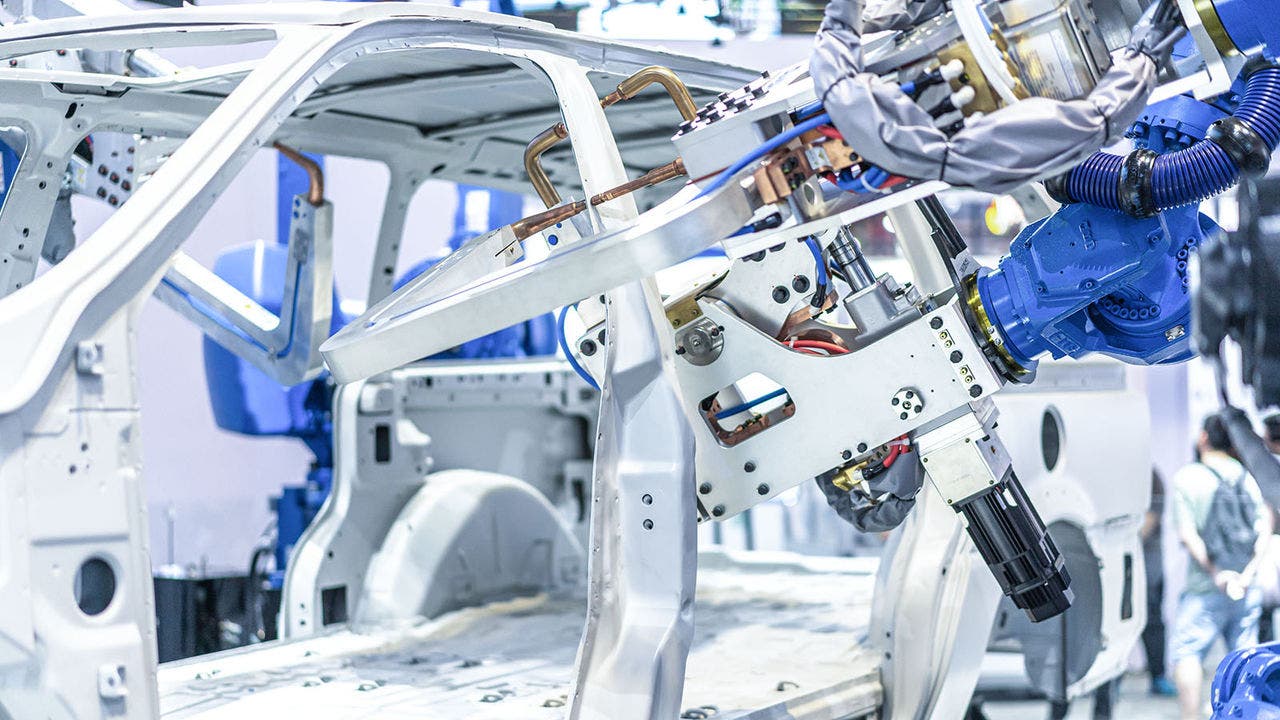 A robotic system equipped with a welding mechanism working on the assembly of a white vehicle chassis in an automotive manufacturing facility