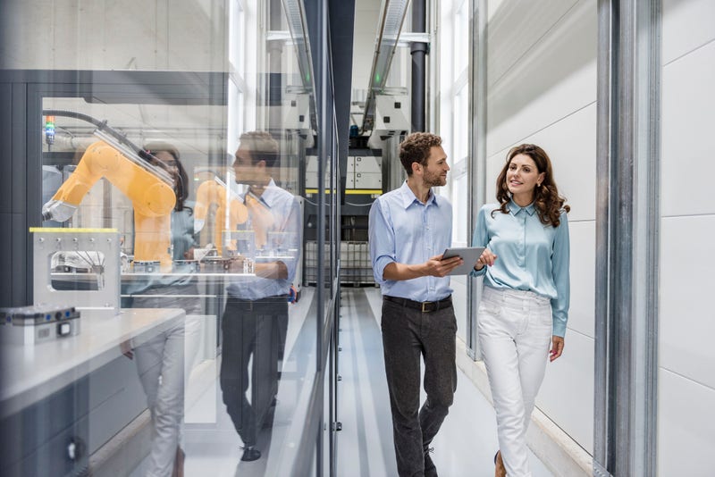 Businessman and woman having a meeting in high tech company using Stäubli robots.