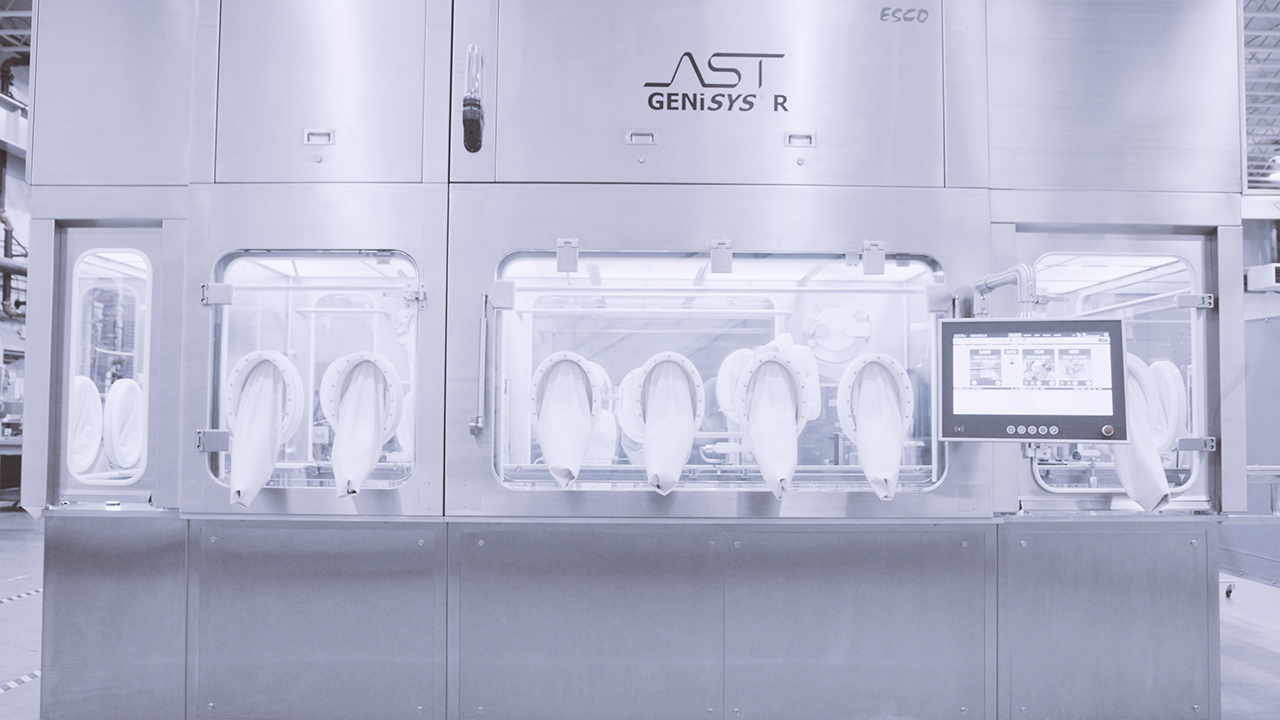 Front view of isolated GENiSYS R aseptic small batch filling and closing machine, showing glove ports and the ASTView human-machine interface (HMI)